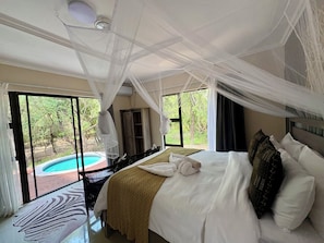 A bedroom with a bed, a window, a ceiling fan, and a view of an outdoor swimming pool.