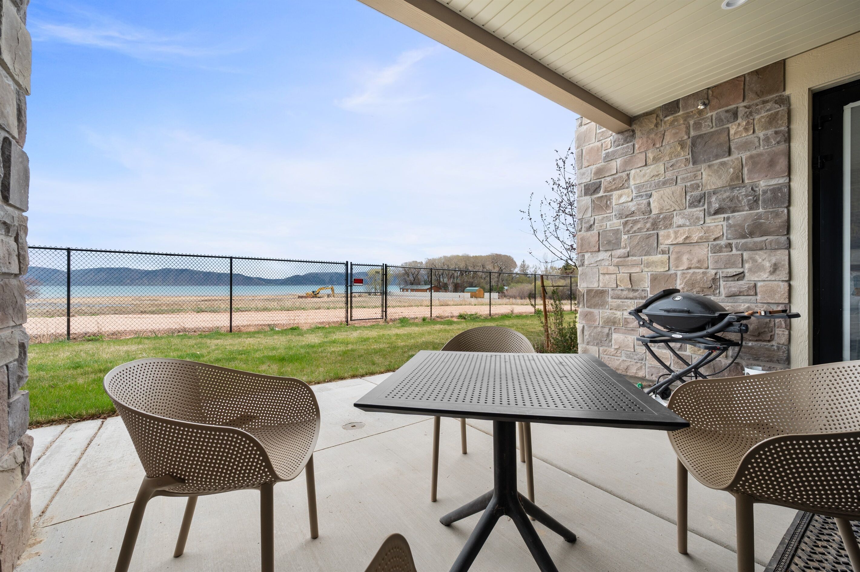 Une terrasse avec une table et des chaises, un barbecue et une vue sur la plage et les montagnes.