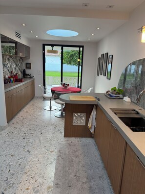 Eine moderne Küche mit Essbereich, großen Fenstern und Blick ins Freie.
