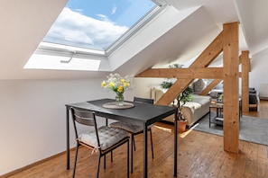 Una habitación con tragaluces, una mesa de comedor con sillas, un sofá y una planta en maceta.