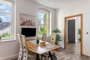 Un coin repas avec une table en bois, des chaises, un téléviseur et des plantes en pot.