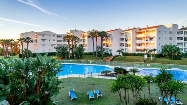 Um hotel com vários andares, piscinas ao ar livre e palmeiras.
