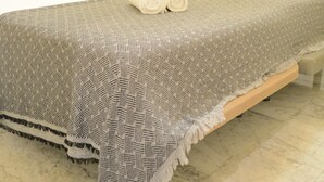 Quarto de hotel com uma cama, mesa de cabeceira e janela com cortinas.