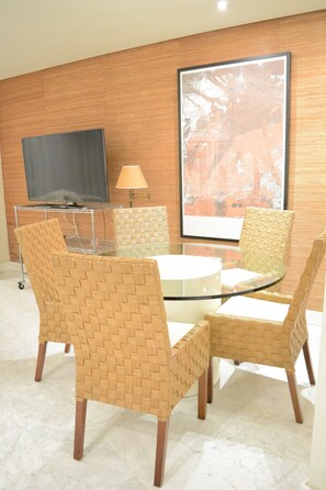 A modern room with a glass-top table, wicker chairs, a flat-screen TV, and a large abstract painting on the wall. - Royal Banus 4, Apartment in Playa Rocío with swimming pool and beach access. (Marbella)