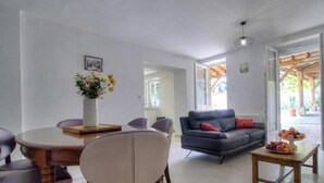 Uma sala de estar moderna com área de jantar, um sofá e uma mesa de centro com frutas.