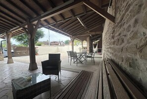 Ein überdachter Außenbereich mit Terrasse, Tisch, Stühlen und einer Bank.