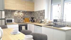 Uma cozinha compacta com micro-ondas, cafeteira e máquina de lavar louça.