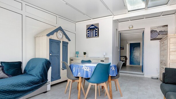 Une pièce avec un lit, une table et des chaises, une horloge et une porte.