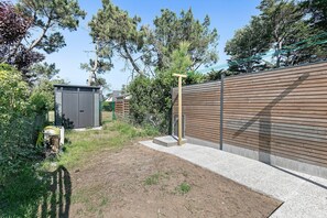 A fenced backyard with a wooden wall, a concrete pathway, and a small shed.