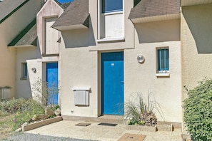 A two-story building with numbered doors, a small window, and a doorbell.