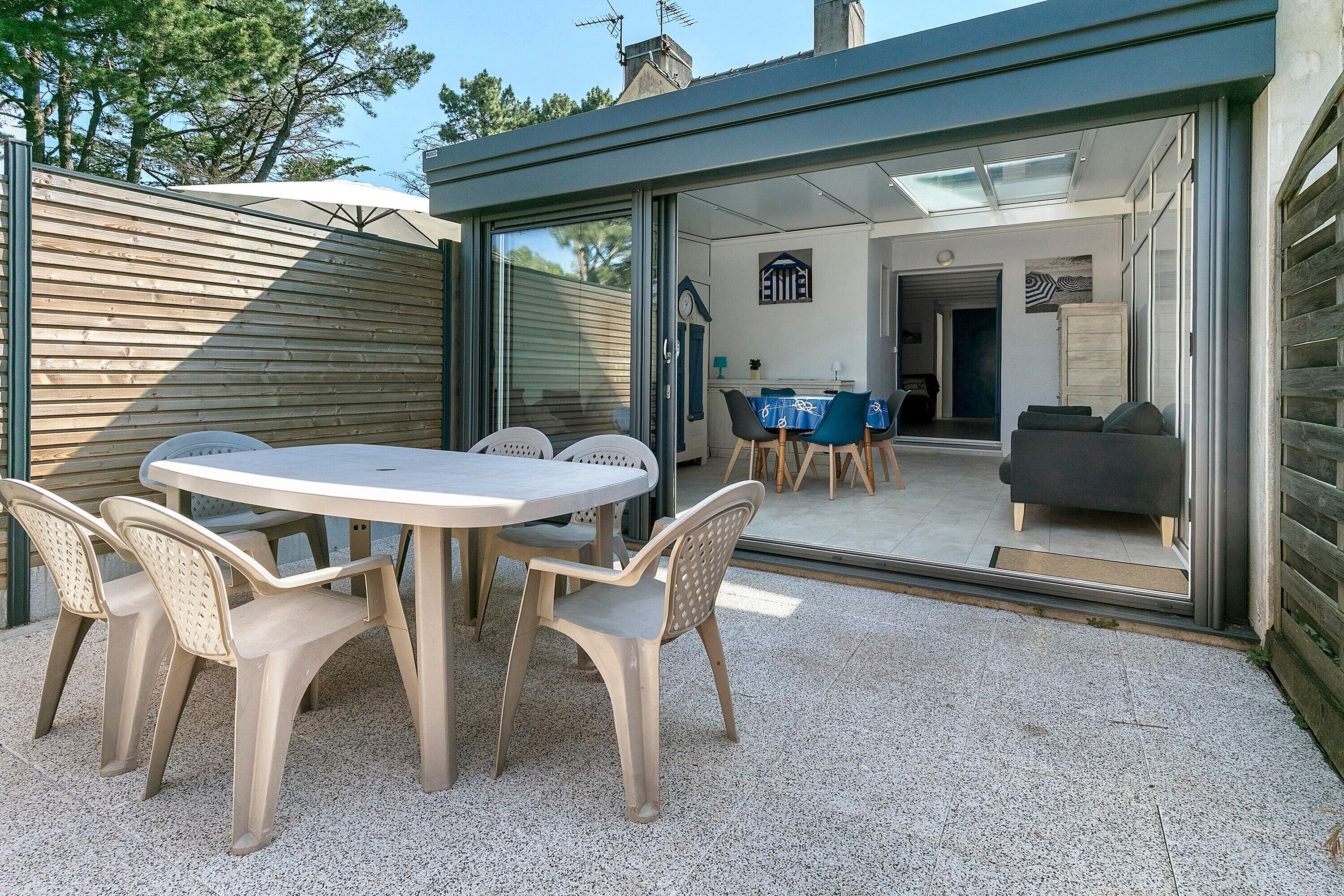 A patio with a round table and chairs, a sliding glass door leading to an interior space, and a view of the outside.