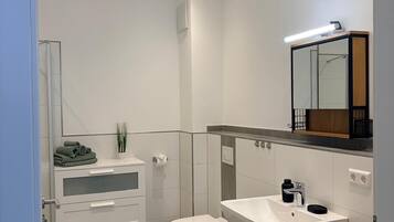 A modern bathroom with a toilet, sink, and storage cabinet.