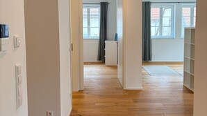 En rymlig hall med trägolv, vita väggar och en taklampa.