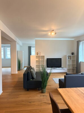 Een moderne woonkamer met een bank, een televisie en een houten eettafel.
