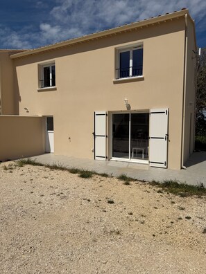 A two-story building with a flat roof, a large sliding glass door, and a small window on the upper floor. - Beautiful new house in a quiet, restful location (Saint-Laurent-des-Arbres)