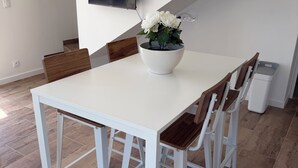 Un comedor moderno con una mesa blanca, sillas de madera y un cuenco blanco con flores.