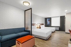 Ein Hotelzimmer mit einer Couch, zwei Betten, einer Trennwand und einem großen Fenster.
