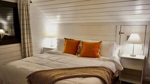 A bedroom with a bed, two bedside tables, a nightstand, a mirror, and a lamp. - Quiet Moose Cabin: 2-bedroom cabin, Mountain views, Hot tub for cozy getaway (Bailey)