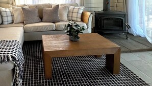 A cozy living room with a sofa, a coffee table, and a fireplace. - Quiet Moose Cabin: 2-bedroom cabin, Mountain views, Hot tub for cozy getaway (Bailey)