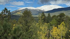 A mountainous landscape with snow-capped peaks, dense forest, and a clear sky. - Quiet Moose Cabin: 2-bedroom cabin, Mountain views, Hot tub for cozy getaway (Bailey)