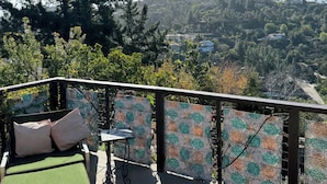 A balcony with a green cushioned sofa, a small table, and patterned privacy screens. - San Deigo Mountaintop Retreat -- SPECTACULAR! (La Mesa)