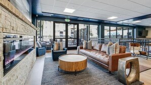 Et moderne loungeområde med stenvæg, behagelige siddepladser og store vinduer med udsigt over byen.