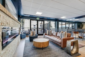 A modern lounge area with a stone wall, seating, a round wooden coffee table, and large windows. - Remodeled Ski-In/Out Studio, King Bed, Hot Tubs, Peak 9, with AC (Breckenridge)