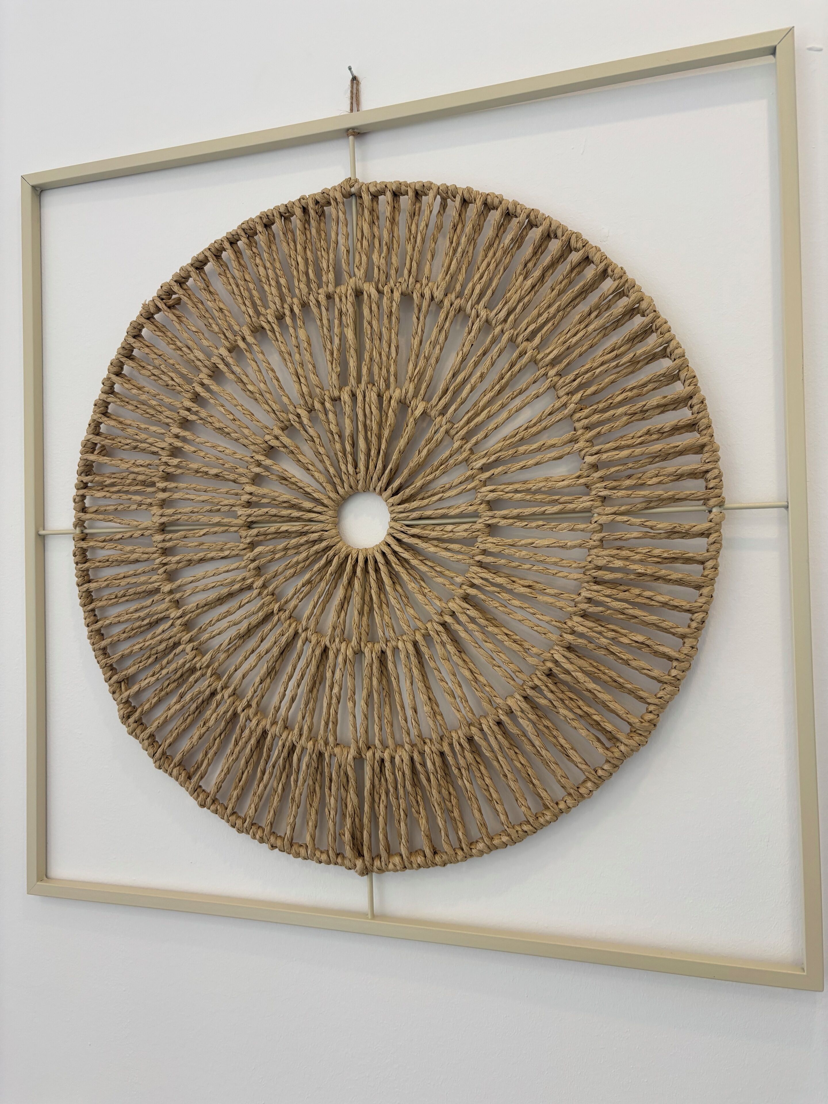 Une œuvre d’art murale circulaire, tissée, fixée au mur.