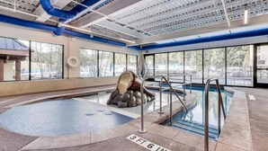 Una piscina interior con una escultura de piedra, ventanas amplias y un techo con conductos a la vista.