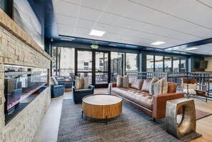 Un espace de détente moderne avec un mur en pierre, des sièges confortables et de grandes fenêtres offrant une vue sur la ville.