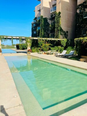 A swimming pool with lounge chairs and greenery. - Eagles Nest/  Private 2BR Oceanview/ Private Rooftop (Cabo San Lucas)