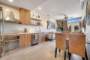 A modern kitchen with built-in appliances, wooden cabinetry, and a dining area with chairs and a table. - Eagles Nest/  Private 2BR Oceanview/ Private Rooftop (Cabo San Lucas)