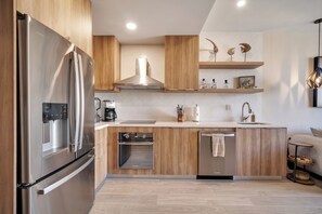 Eine moderne Küche mit Edelstahlgeräten, Holzschränken und einem eingebauten Ofen.