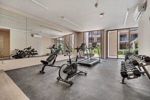 Ein Fitnessstudio mit Trainingsgeräten, großen Fenstern und Blick nach außen.