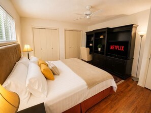Ein Hotelzimmer mit Bett, Fernseher, Deckenventilator und Kleiderschrank.