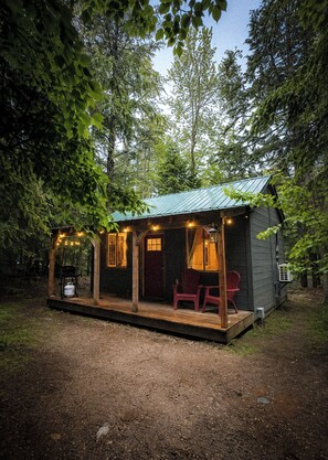 A small cabin with a porch, a table, and two chairs. - Henrys cabin on the river (Northbrook)