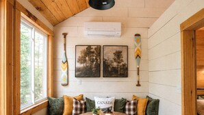 Een gezellige kamer met een houten plafond, een ronde tafel met dienblad, en een bank met kussens.