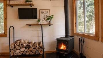 A cozy room with a fireplace, a television mounted on the wall, and a sign that reads 'RAISE THEM HIGH.'