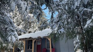 A small cabin with a porch, two red Adirondack chairs, and snow-covered trees. - Henrys cabin on the river (Northbrook)