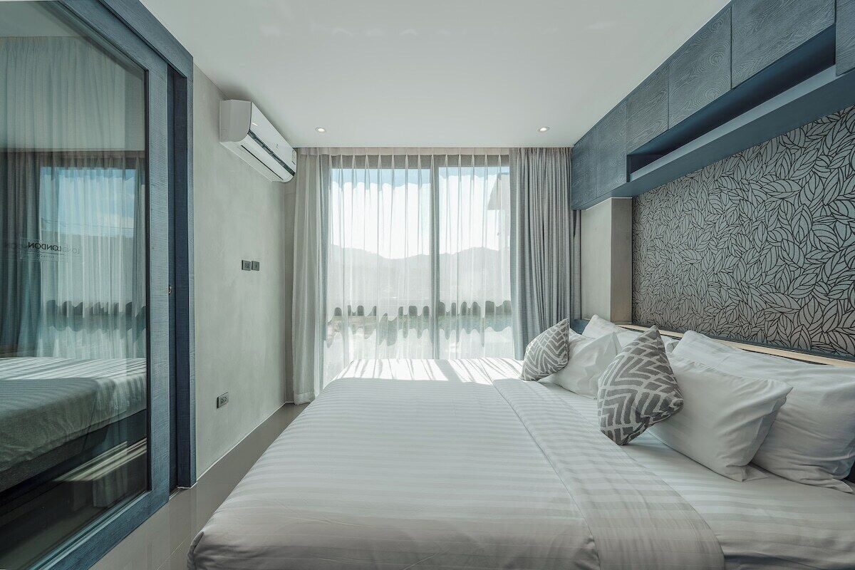 Quarto de hotel moderno com uma cama grande, vista pela janela e parede com padrão.
