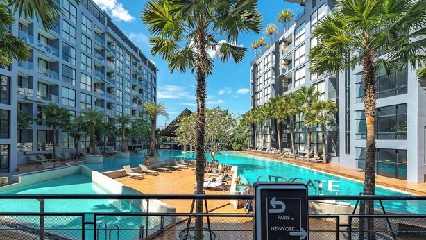 Un hôtel doté d’une piscine, de palmiers et d’un panneau indiquant « 5 Paris New York ».