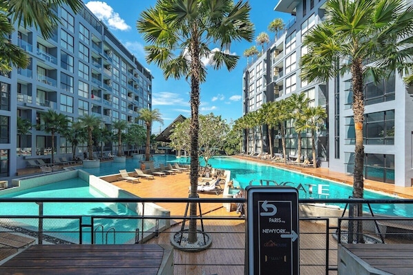 Ein Hotel mit Poolbereich, Palmen und einem Schild mit der Aufschrift '5 Paris NewYork'.