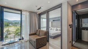 Une chambre d’hôtel moderne dotée d’un balcon, d’un lit, d’un canapé et d’une salle de bain avec douche et toilettes.