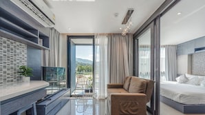 Une chambre d’hôtel moderne dotée d’un balcon, d’un canapé, d’un lit, d’un bureau et offrant une vue sur l’extérieur.