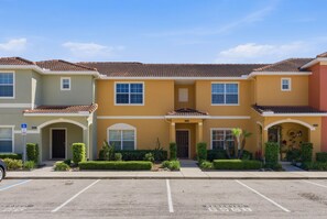 A row of three-story buildings with a parking lot in front. - Stylish 4br, Private Pool, Themed Rooms, Sleeps 13 (Kissimmee)