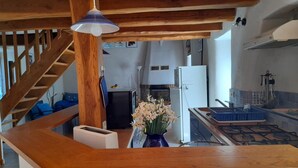 Une cuisine équipée d’une cuisinière à gaz, d’un réfrigérateur blanc et d’un évier bleu.