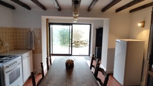 A kitchen with a stove, dining table, chairs, and a refrigerator. - Balcon des Fées - MALZIEU VILLE (LE) (MALZIEU VILLE (LE))