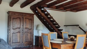 A dining area with a wooden table, chairs, and a large cabinet. - Balcon des Fées - MALZIEU VILLE (LE) (MALZIEU VILLE (LE))