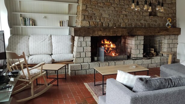 A living room with a stone fireplace, a sofa, a rocking chair, a coffee table, and a bookshelf. - Balcon des Fées - MALZIEU VILLE (LE) (MALZIEU VILLE (LE))