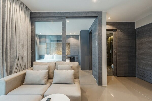 Ein modernes Hotelzimmer mit einer Couch, einer Fernbedienung und einer Glaswand.